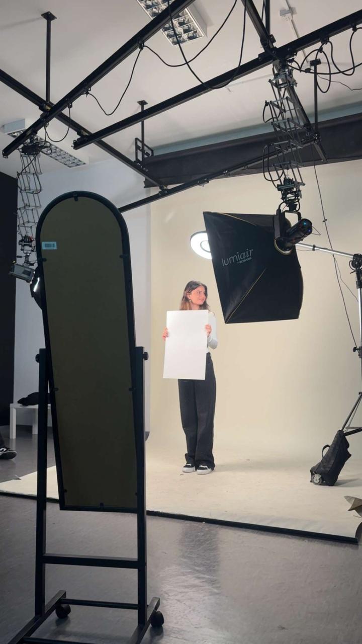 Leya Awad — behind the scenes in the studio holding a reflector board